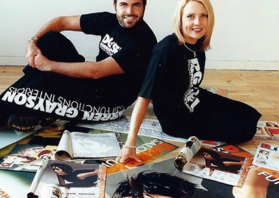 darren grayson and a lady sitting on some magazines on the floor
