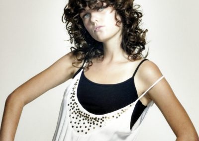lady with long curly hair wearing black and white sleeveless tops