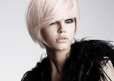 lady with short light pink hair wearing a black feather top